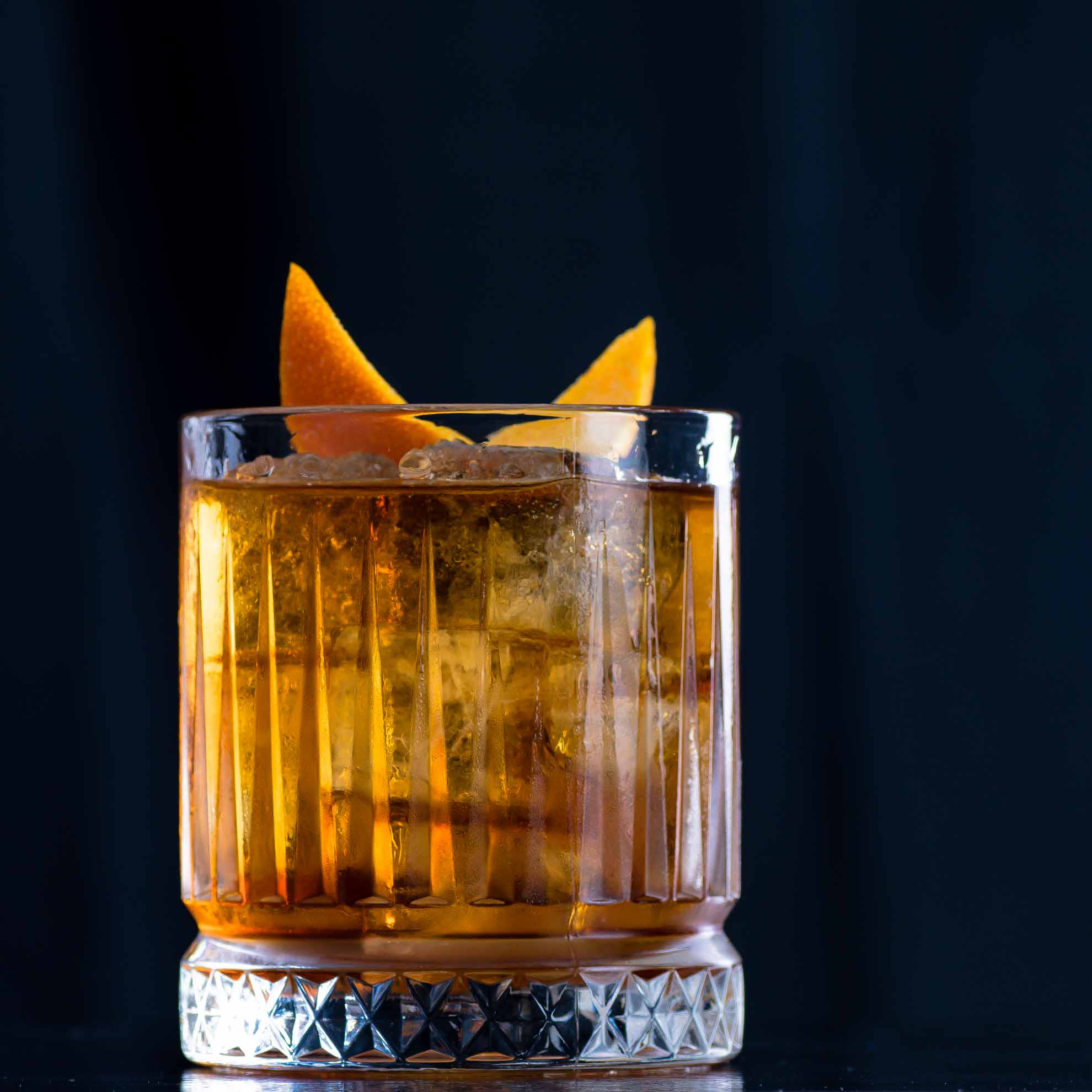 Ein Old Fashioned Cocktail mit Bourbon Whiskey, Bitters, Zuckersirup und Orangenzeste.