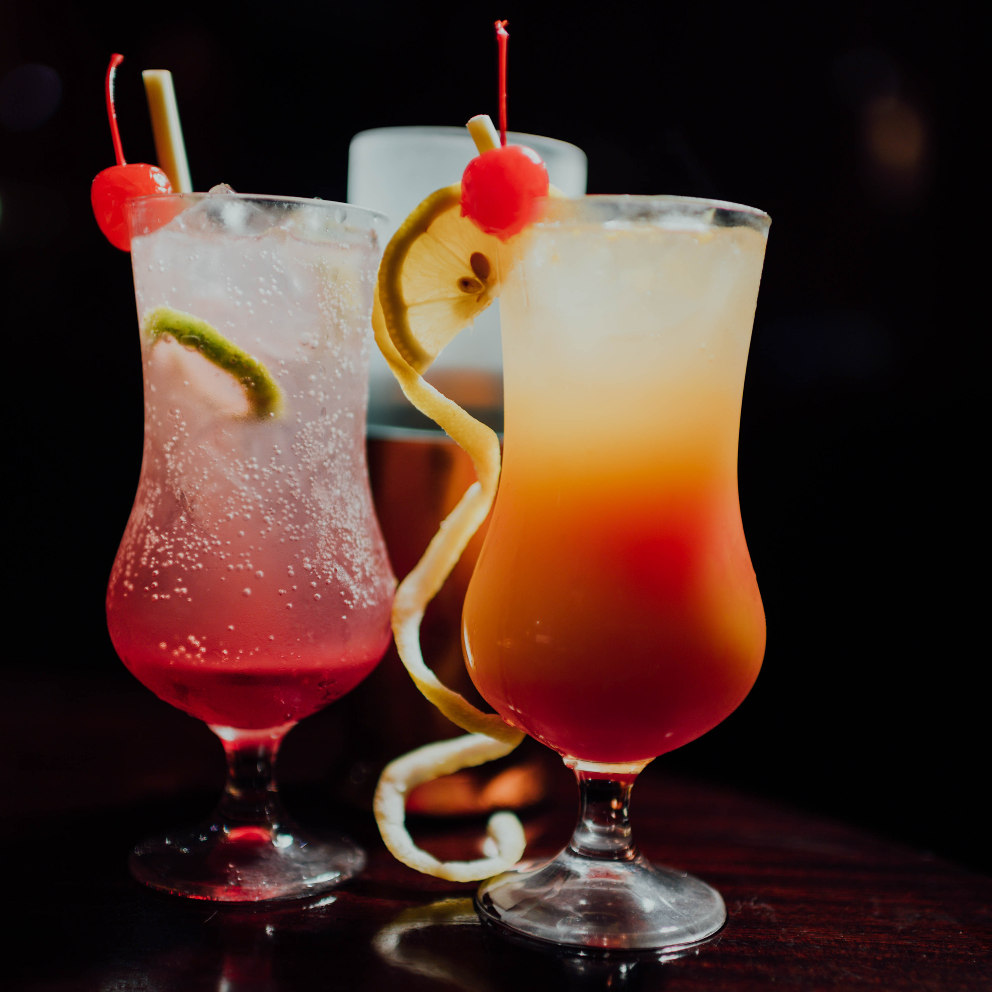 Verschiedene Cocktails in Hurricane-Gläsern.