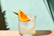 Ein Negroni Bianco Cocktail, garniert mit einem Stück Orange.